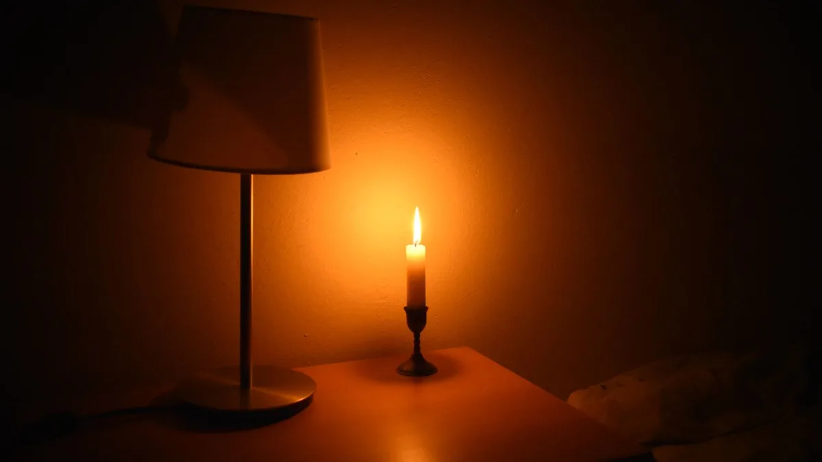 Zapalona świeca i lampa w ciemnym pokoju podczas przerwy w dostawie prądu