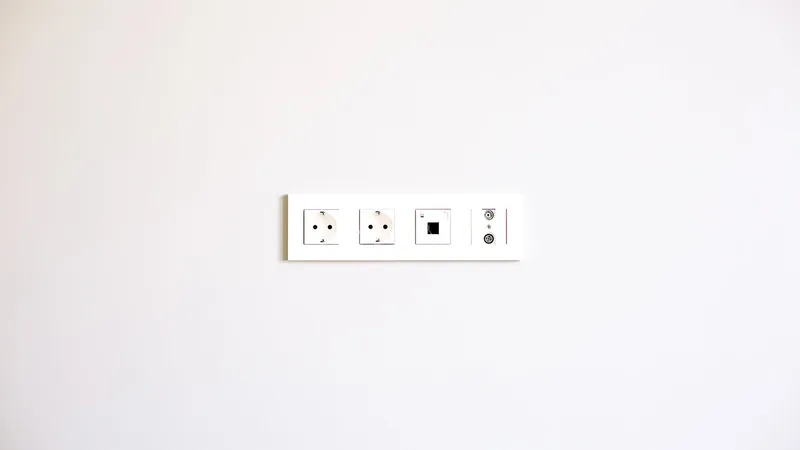 Gniazdka elektryczne i włącznik zamontowane na białej ścianie